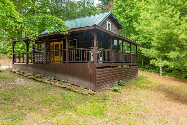 Une cabane dotée d’un porche couvert, d’une porte d’entrée et d’une petite terrasse.