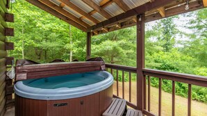Un jacuzzi en una terraza de madera con vista a un bosque.