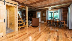 Un interior de madera con una zona de comedor, un sofá y una escalera.