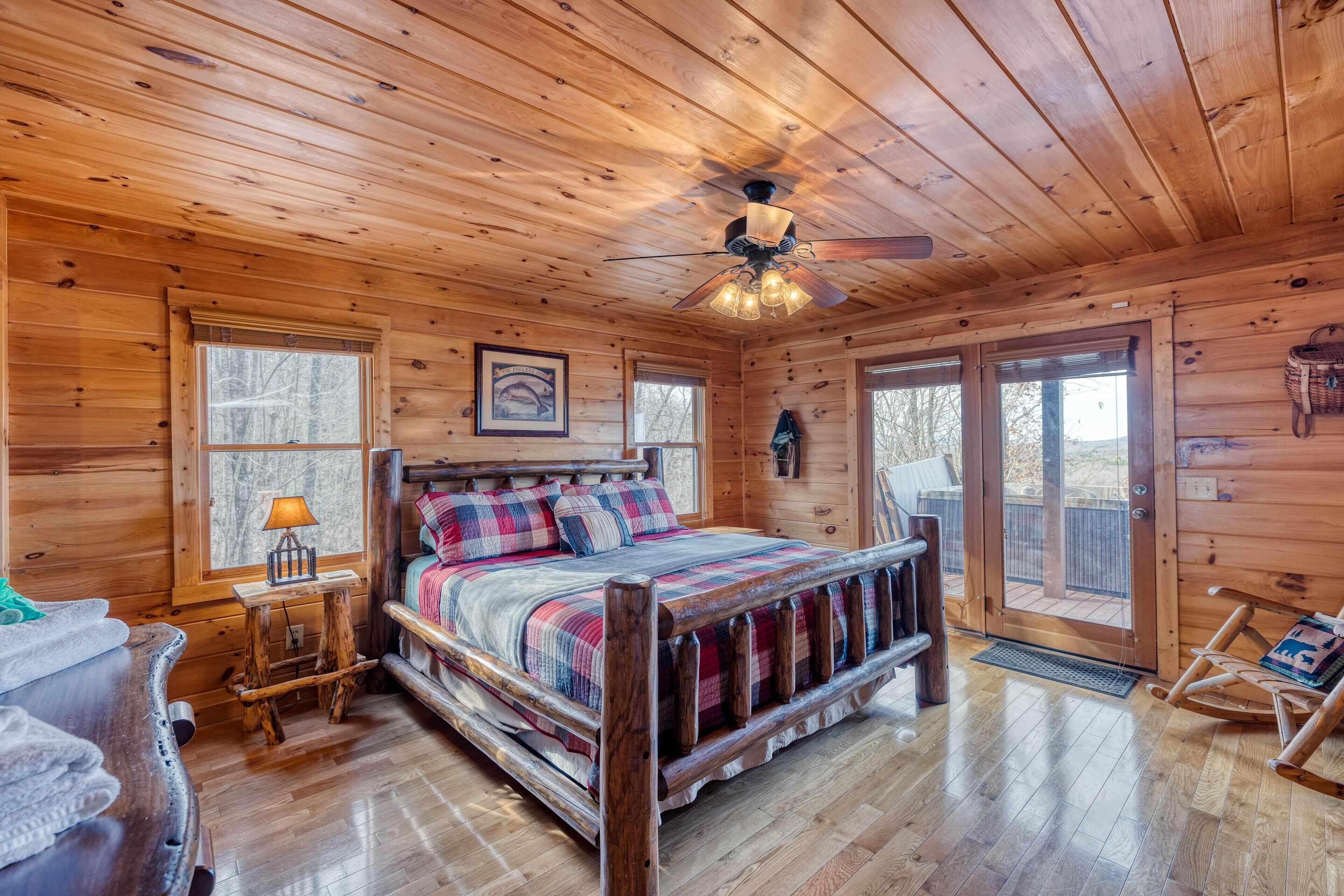 Une chambre dans une cabane en bois, avec un lit, un ventilateur de plafond et une fenêtre.