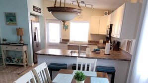 A dining room with a wooden table, white chairs, and a chandelier. - Lower Keys paradise (Cudjoe Key)