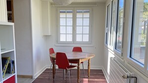 En matplats med ett träbord och röda stolar, stora fönster och ett vitt tak.