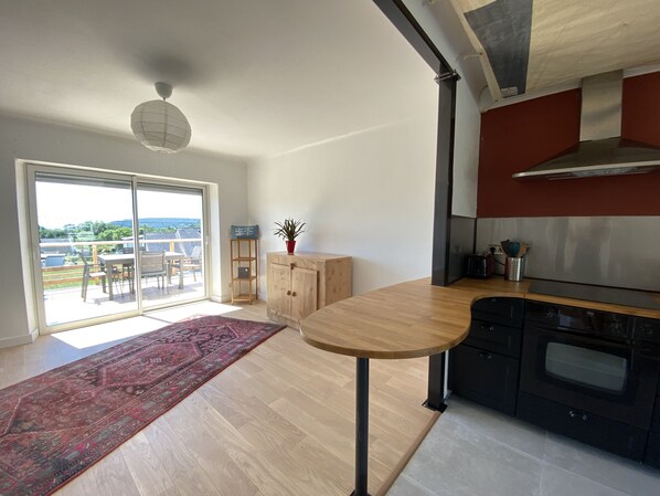 A modern kitchen with a wooden table, a built-in oven, and a sliding glass door leading to a balcony.
