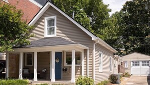 Een gelijkvloers huis met een veranda, een garage en een kleine aangebouwde schuur.
