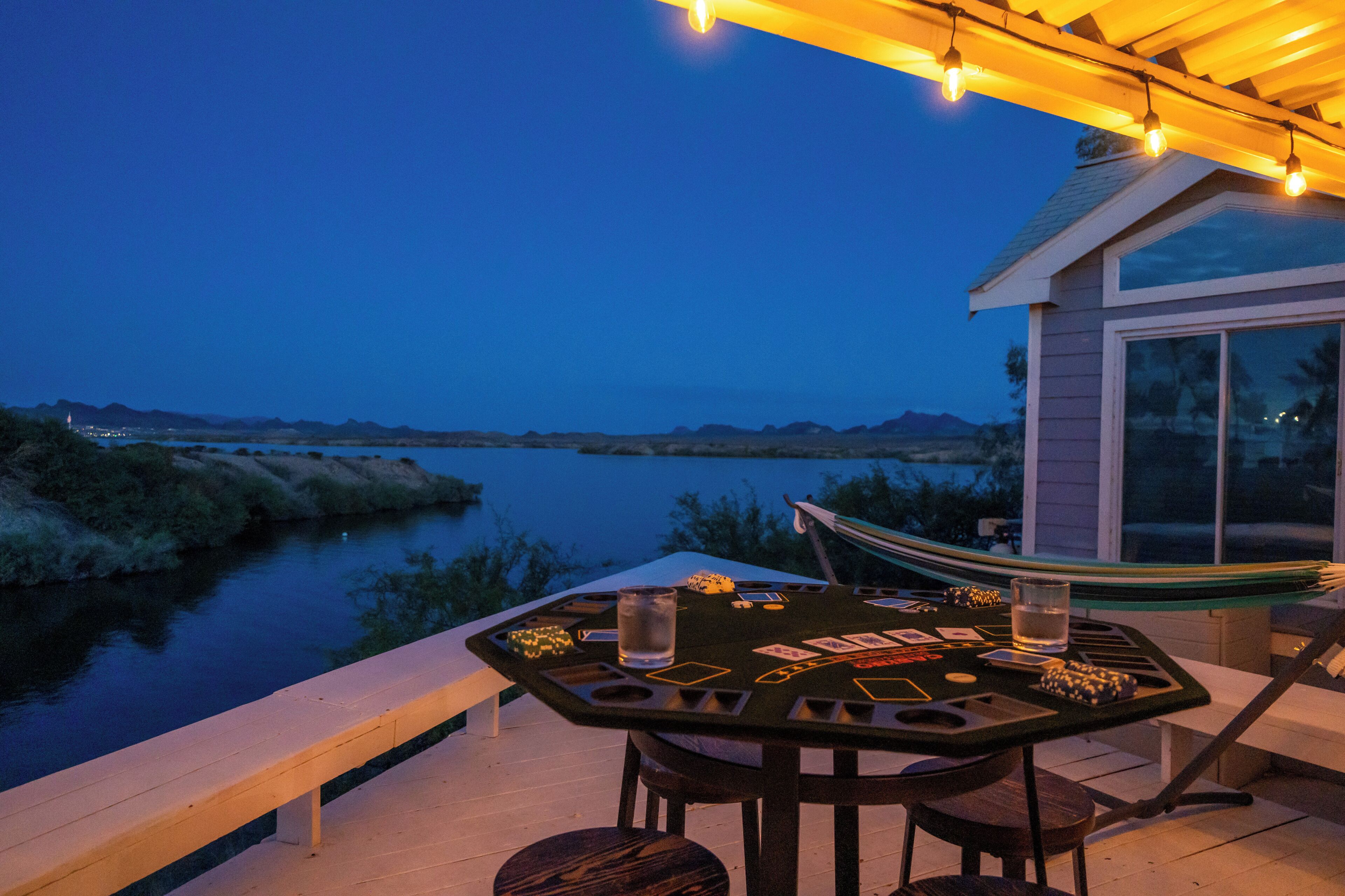 Una terraza con una mesa lista para un juego, con vista a un río y montañas.