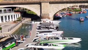 Un port de plaisance où sont amarrés différents types de bateaux, un pont en arrière-plan et un ciel dégagé.