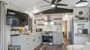 Eine moderne Küche mit weißen Schränken, einer eingebauten Mikrowelle, einem Backofen und einem Deckenventilator.