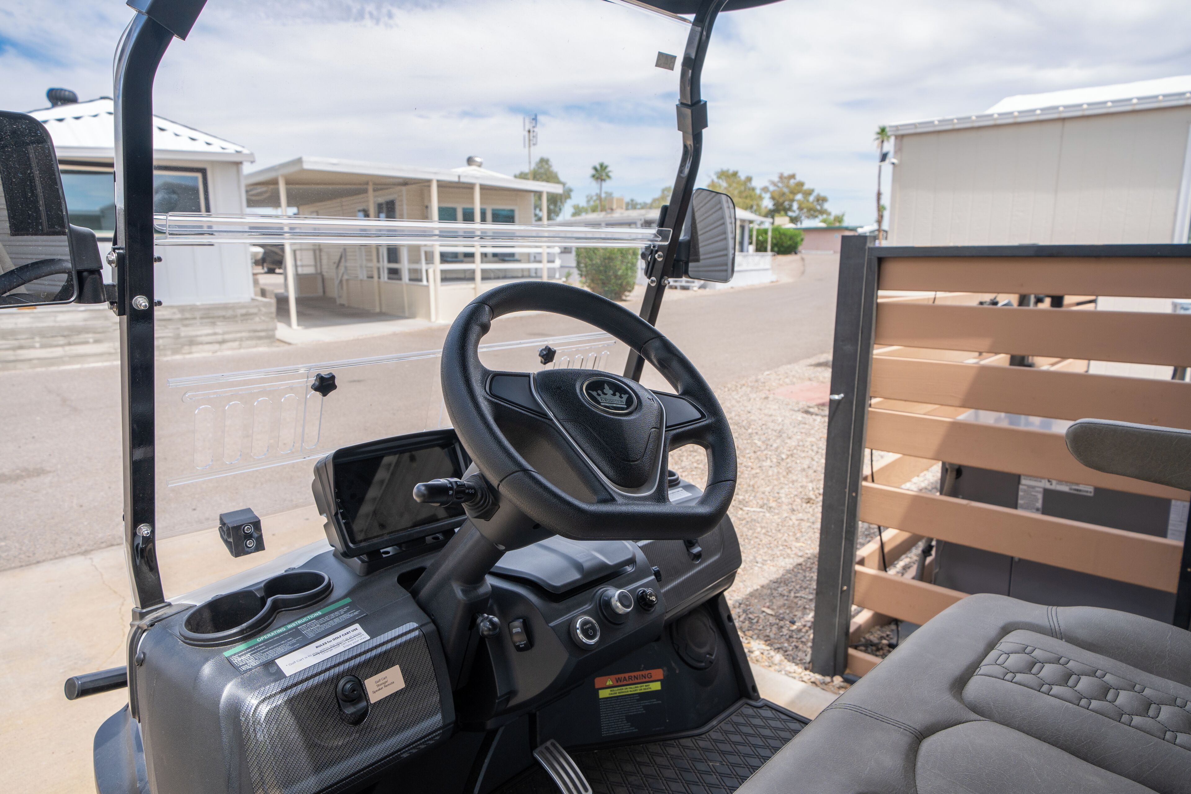 A golf cart interior with a steering wheel, control panel, and seating area.