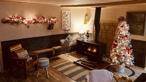 Uma sala de estar aconchegante com lareira, árvore de Natal e um banco de madeira.
