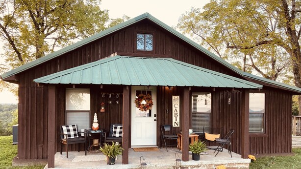 Uma cabana rústica com varanda, área de estar e uma placa que diz "Relax Cabin".