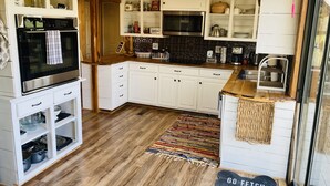 Cozinha com armários brancos, micro-ondas, forno e teto de madeira.