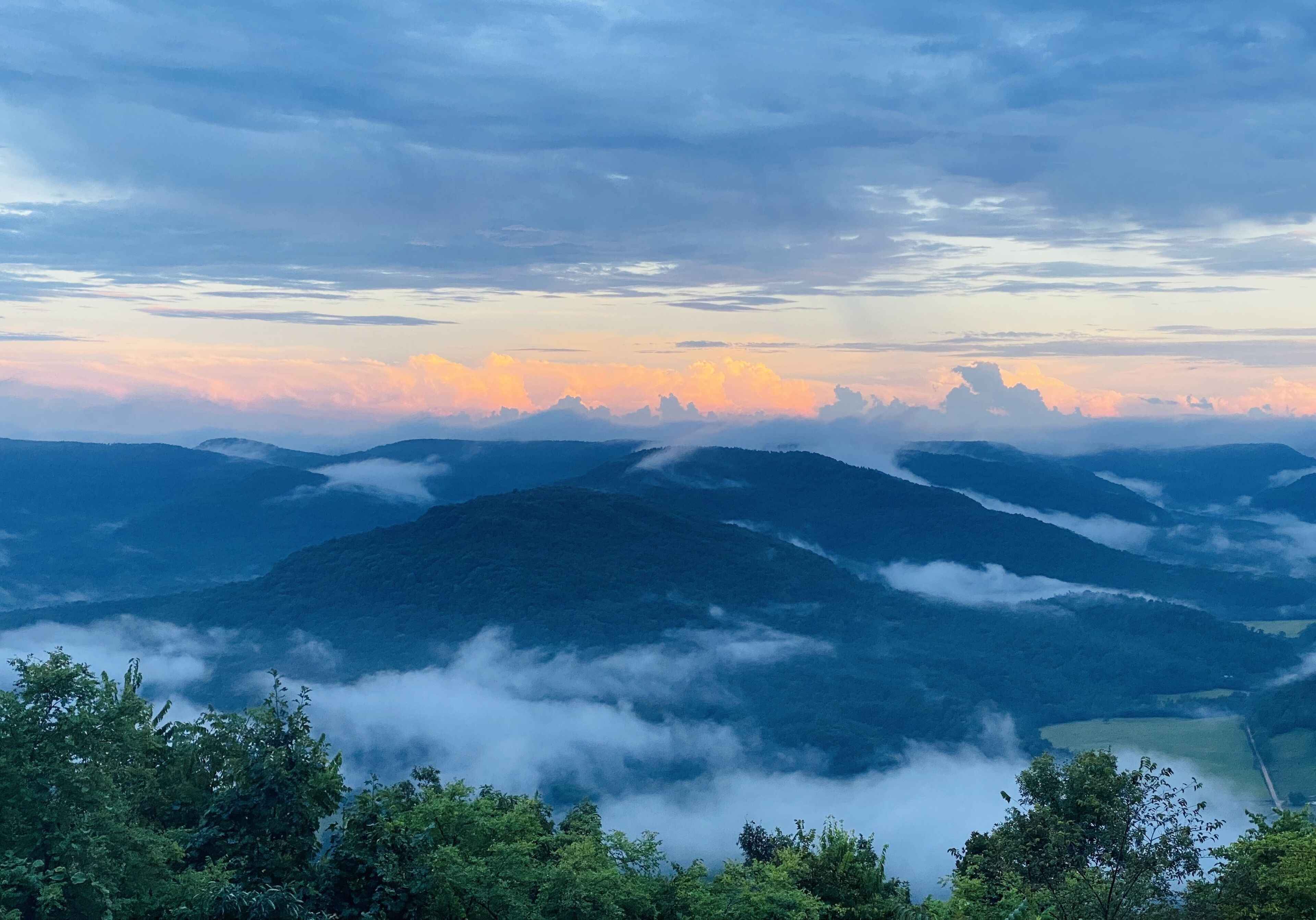 A mountainous landscape with a view of the sky at sunset.