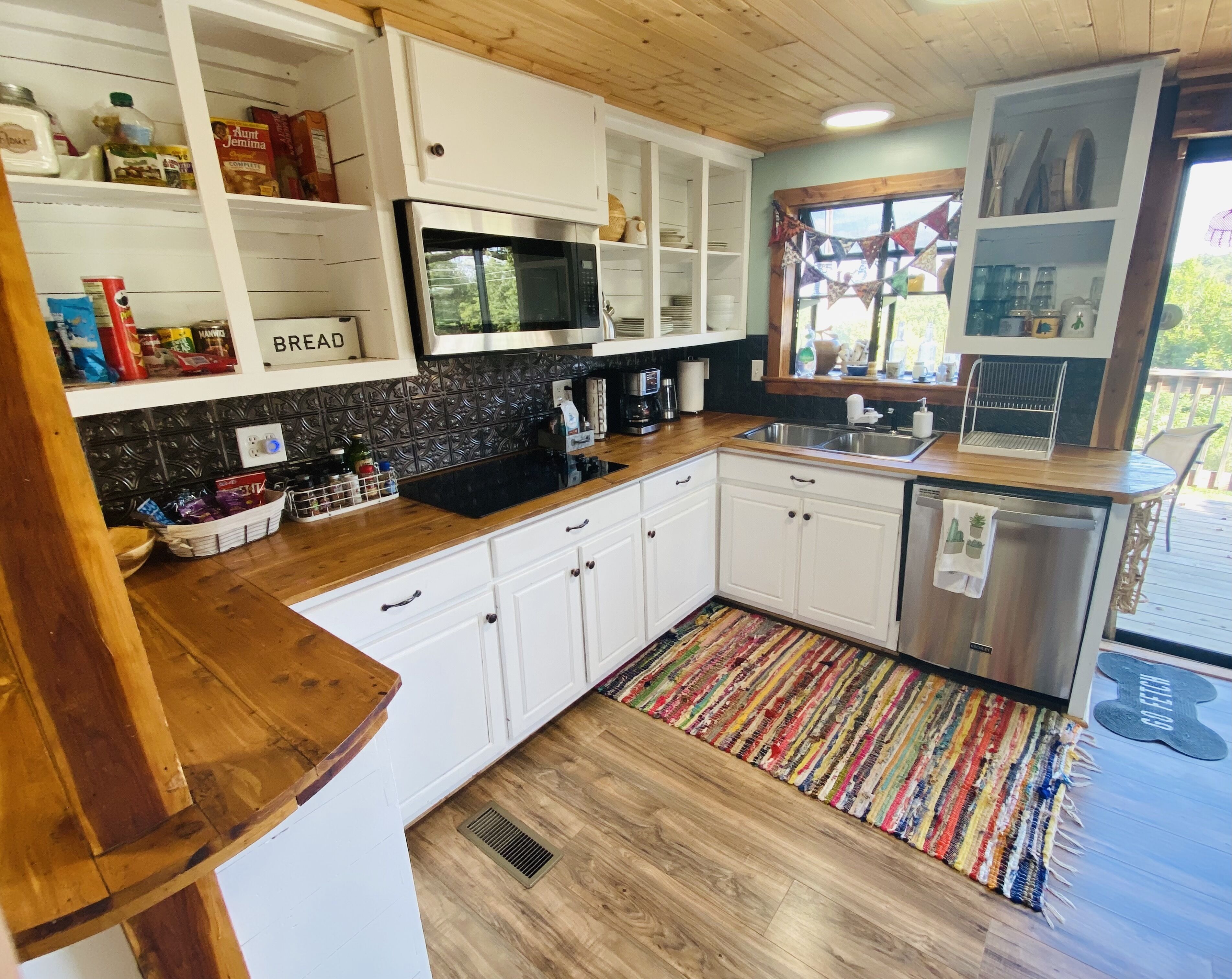 A kitchen with white cabinets, a microwave, a sink, and a coffee maker.