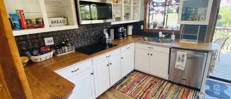 A kitchen with white cabinets, a microwave, a sink, and a coffee maker.