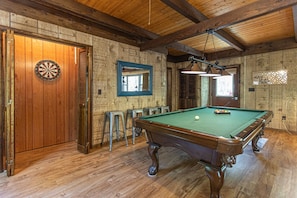 Une table de billard dans une pièce aux murs et au plafond en bois.