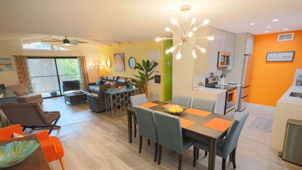 A modern living room with a dining area, a kitchen, and a balcony.