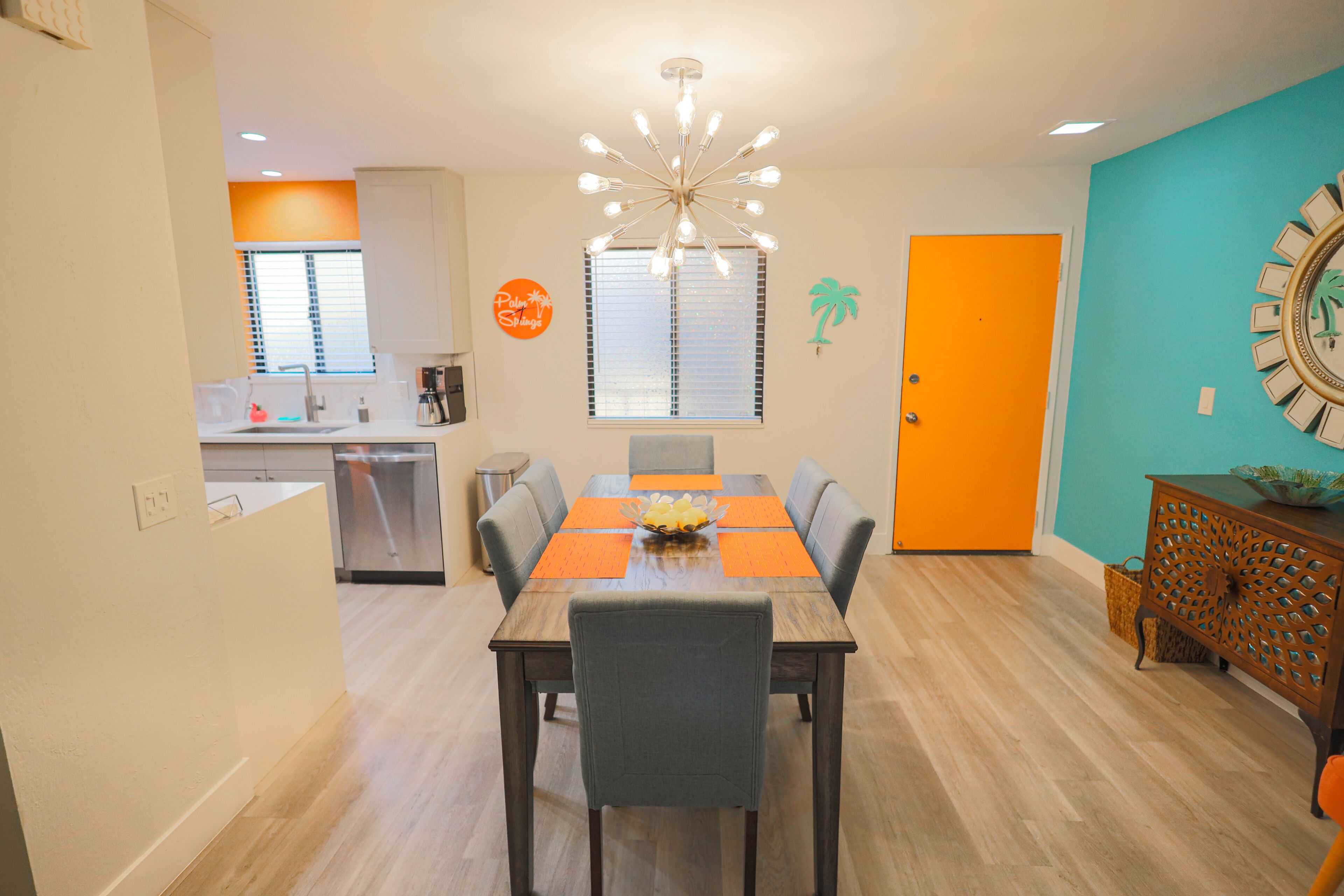 A dining area with a wooden table, chairs, and a modern chandelier.