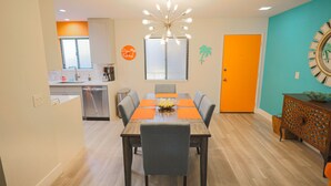A dining area with a wooden table, chairs, and a modern chandelier.