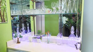 A bathroom with a glass display shelf above a white countertop, featuring various glassware.