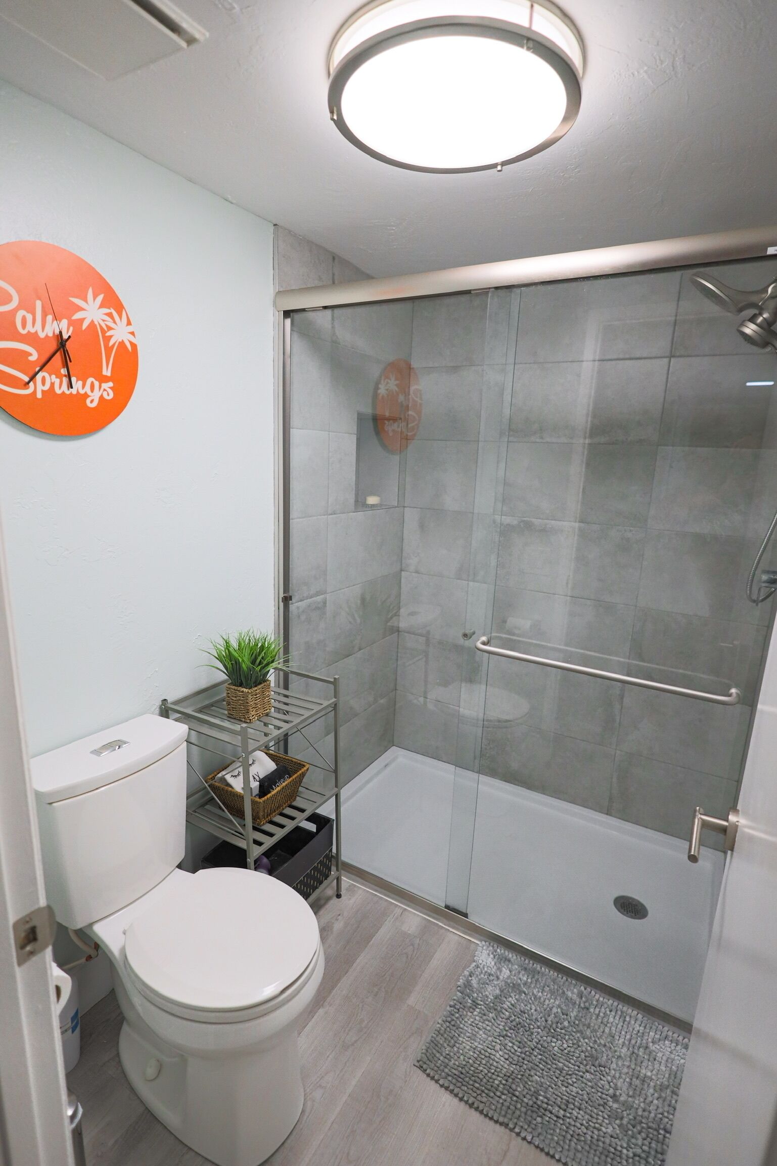 A modern bathroom with a toilet, shower, and a glass-enclosed shower stall.