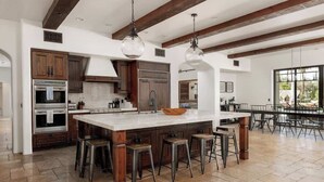 A spacious kitchen with a large island, wooden cabinets, and bar stools. - ParadiseValleyMillion$ Estate+Golf+Boccee+Casita (Paradise Valley)