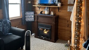 Una sala de estar acogedora con chimenea, televisión y un cartel que anuncia actividades invernales.