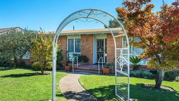 A house with a brick facade, a front porch, and a white metal archway.