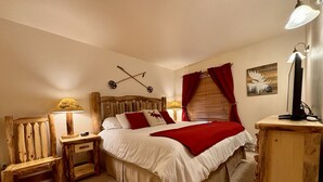 A bedroom with a wooden headboard, a bed with white bedding and red accents, two bedside lamps, a wooden nightstand, and a desk with a lamp. - Moose Ski Condo in Canyons Village of Park City 3-minutes from Slopes & Trails! (Park City)
