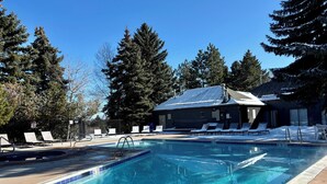 A clear blue pool with lounge chairs and a building in the background. - Moose Ski Condo in Canyons Village of Park City 3-minutes from Slopes & Trails! (Park City)