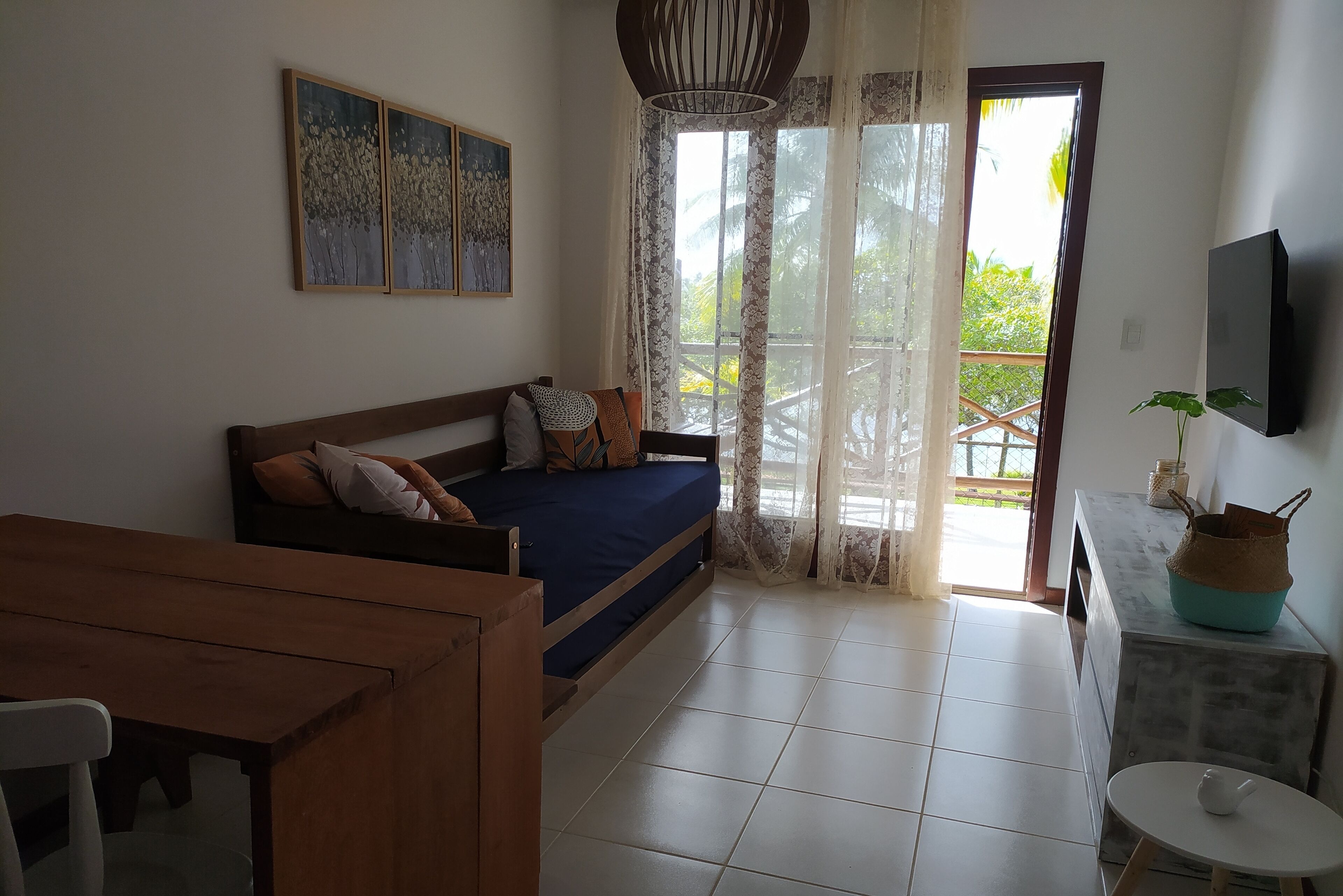 A bedroom with a bed, a wooden bench, a small table, and a TV.