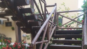A wooden staircase with a handrail, surrounded by greenery and red flowers. - Itacimirim Villages (Itacimirim)