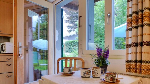 A kitchen with a table set for two, a microwave, and a window with curtains.