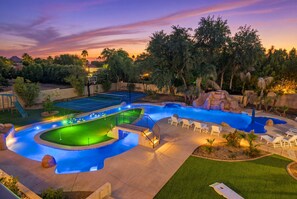 A landscaped pool area with a basketball court, a waterfall feature, and lounge chairs.
