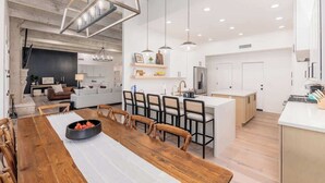 Une cuisine moderne avec des meubles blancs, un îlot central et des luminaires suspendus.