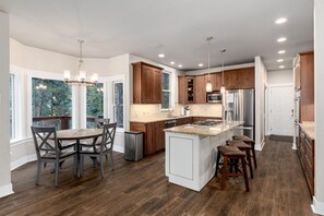 Enjoy cooking in this well-equipped kitchen with a central island, dining area, and large windows.