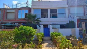 A two-story building with a blue door, surrounded by potted plants and a stone pathway. - Summer Center Imi Ouaddar 5389 (Imi Ouaddar)