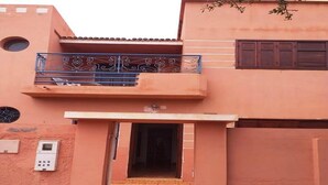 Un edificio de dos pisos con un balcón, una puerta y una ventana pequeña.