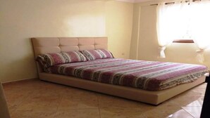 Une chambre à coucher avec un lit, une tête de lit et une fenêtre avec des rideaux.