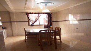 Un espace repas doté d’un sol en marbre, d’une table ronde et de chaises en bois.
