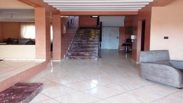 Un hall d’entrée spacieux avec un escalier en marbre menant à un deuxième étage.