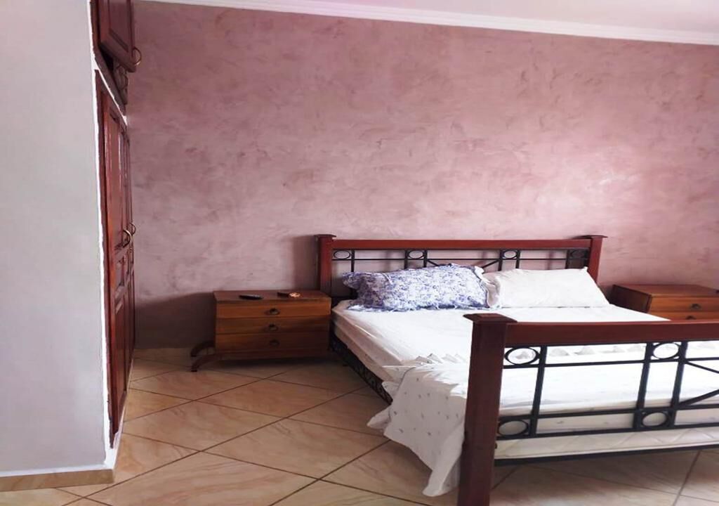 Une chambre à coucher avec un lit en bois, une table de chevet et une armoire.
