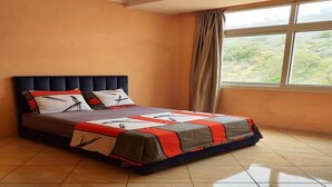 Une chambre à coucher avec un lit, une fenêtre avec des rideaux et une vue sur la verdure à l’extérieur.