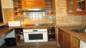 Een keuken met houten kastjes, een magnetron, een oven en een spoelbak.
