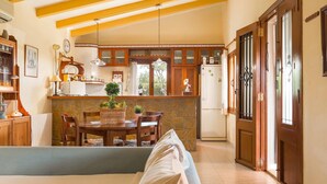 A cozy living room with a dining area, wooden furniture, and a stone fireplace. - Beautiful finca with pool in Selva, in the center of Mallorca. (Selva)