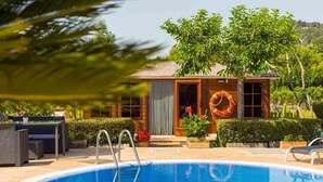 A swimming pool with a wooden deck, a lifebuoy, and a house with a sliding door. - Beautiful finca with pool in Selva, in the center of Mallorca. (Selva)