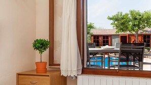 A room with a window overlooking a pool and a building with a red roof. - Beautiful finca with pool in Selva, in the center of Mallorca. (Selva)