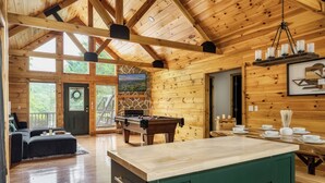 Eine geräumige Holzhütte mit Billardtisch, einer Sitzecke und einem Essbereich.