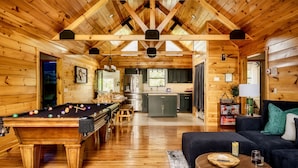 Ein Holzblockhaus-Interieur mit Billardtisch, Sofa und Küchenzeile.