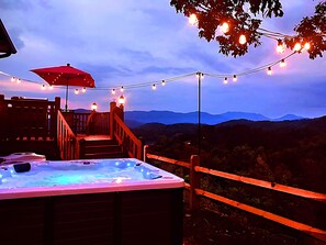 A hot tub with a wooden deck and stairs, surrounded by a wooden fence and string lights. - Heaven’s Kiss ~ Heated Pool ~ Sauna ~ Theater ~ GameRoom ~ Pvt MtnTop ~ Sleeps16 (Sevierville)