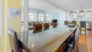 Una sala de estar moderna con una mesa de comedor de vidrio, sillas de cuero marrón y un ventanal grande.